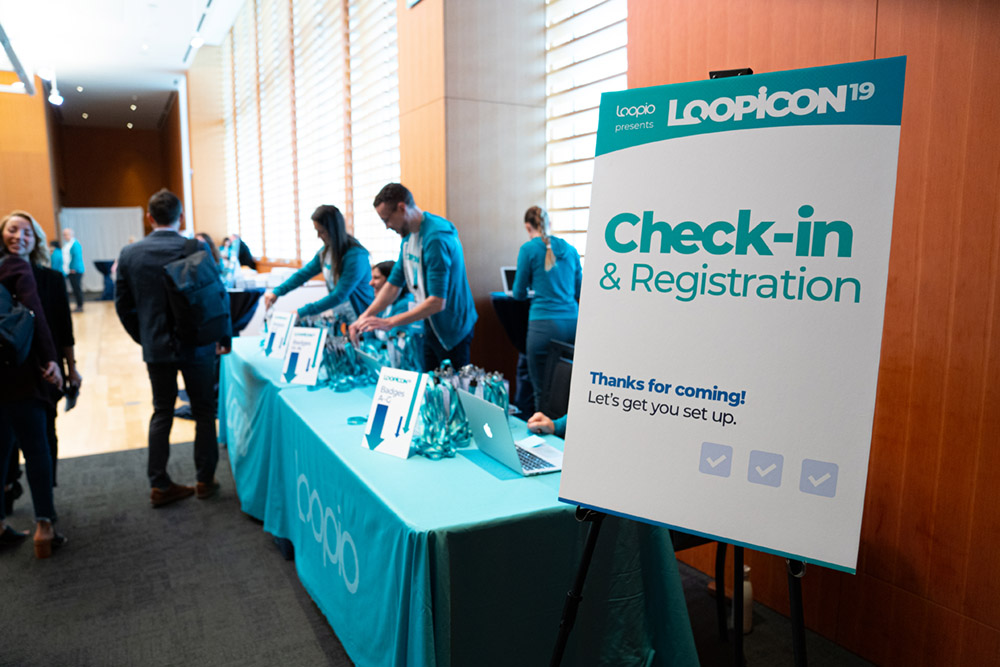 A conference table check-in, with people preparing sorting badges in the background
